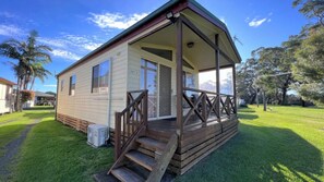 A single-story house with a porch, a small front yard, and a clear sky. - Cottage 3 ~ Family cottage at Sussex House Holiday Park (Sussex Inlet)