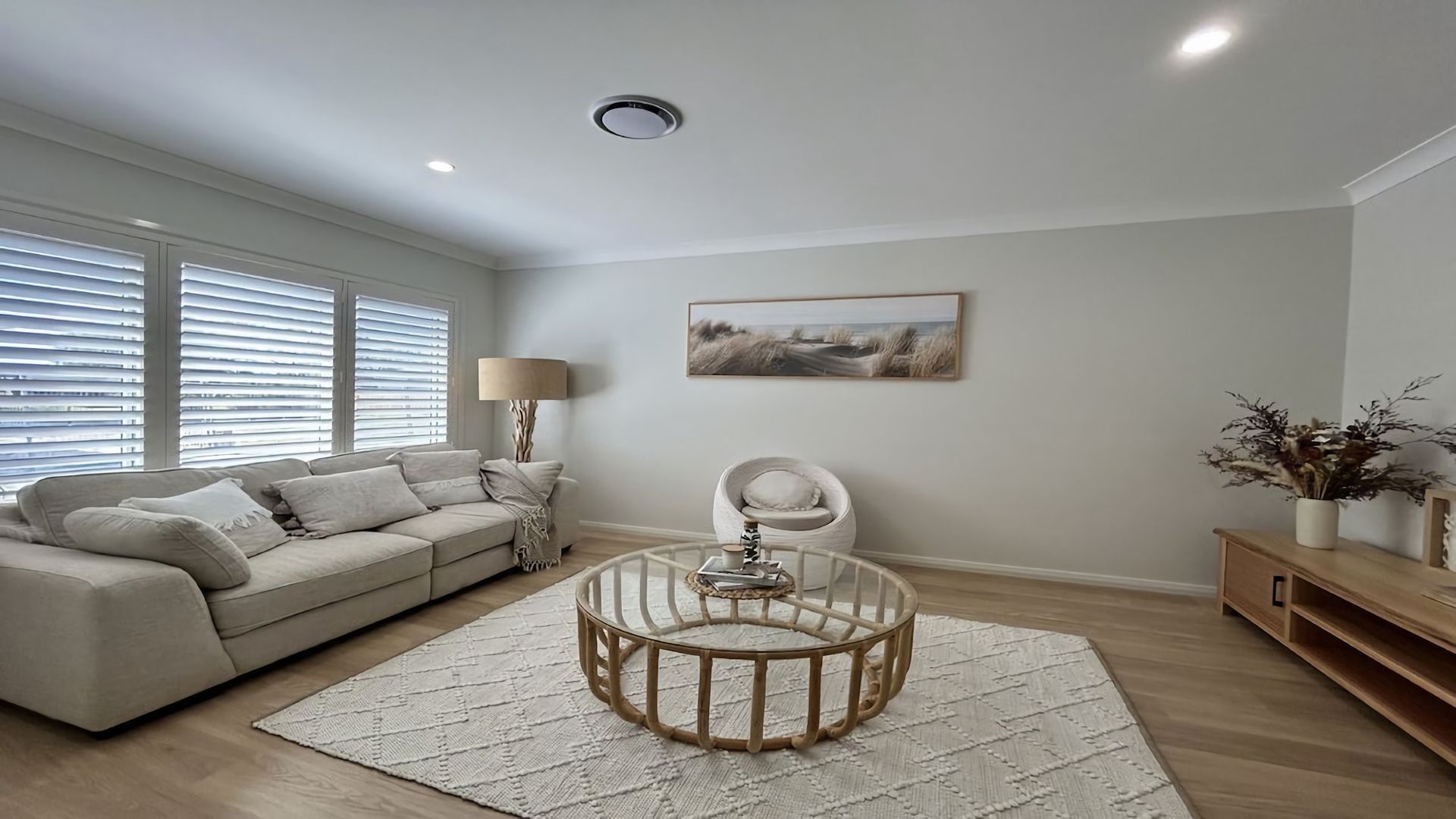 A living room with a sofa, a round coffee table, a lamp, and a painting on the wall.