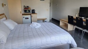 A hotel room with a bed, a desk, a television, and a kitchenette. - Jopen Motel Unit 2 ~ Stress-free, affordable, and comfortable (Sussex Inlet)