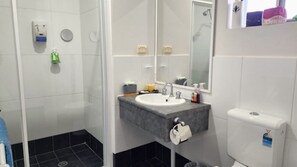 A bathroom with a white sink, a mirror, a towel rack, and a toilet.