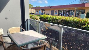 A balcony with wicker furniture and a table, overlooking a building with a red roof and a sign that reads 'Hotel'. - Jopen Motel Unit 3 ~ Stress-free and comfortable! (Sussex Inlet)