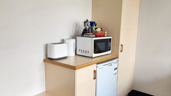 A kitchenette with a microwave, toaster, and a small refrigerator.