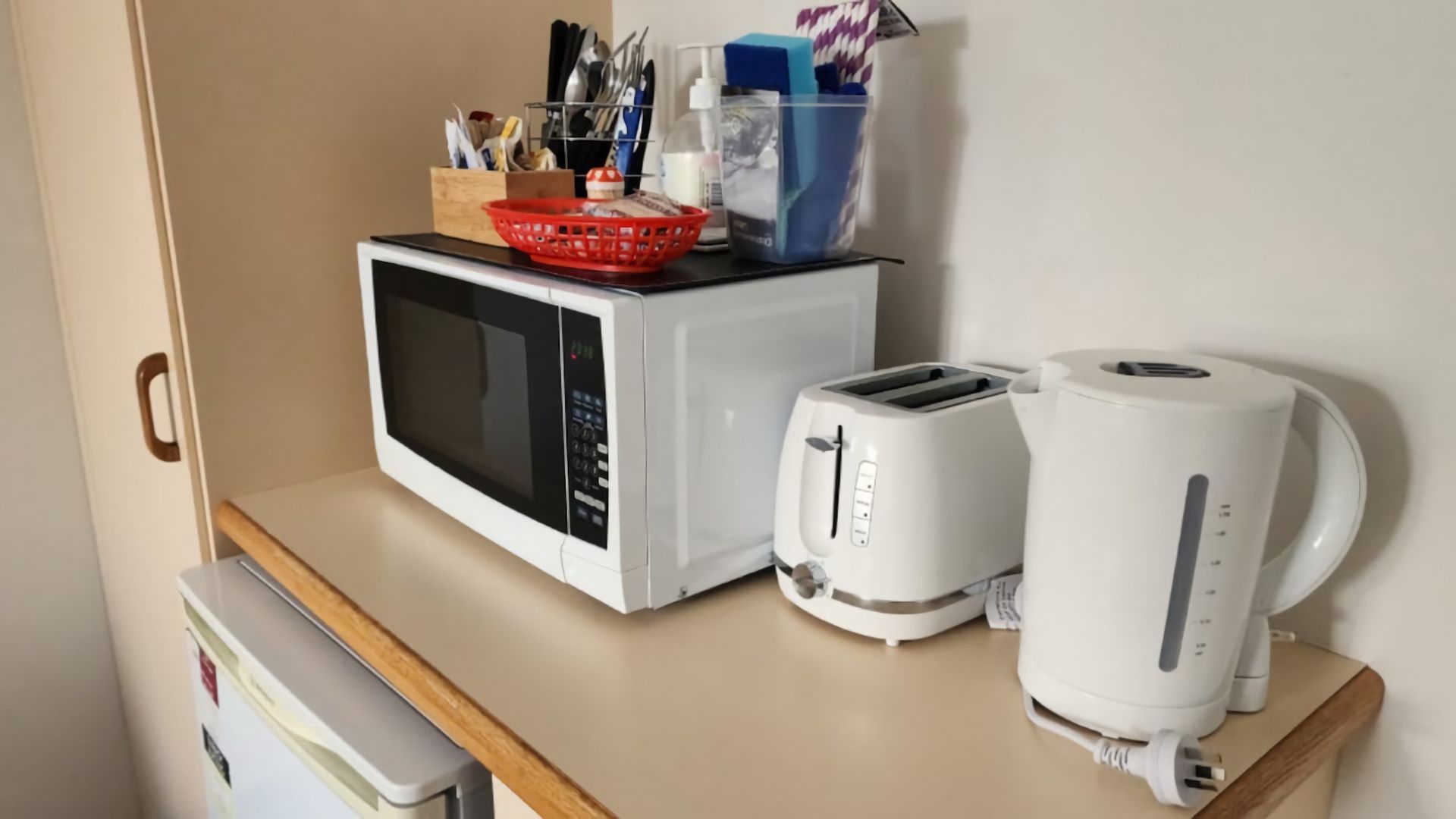 Een kitchenette met een magnetron, toaster en koffiezetapparaat op een aanrecht.