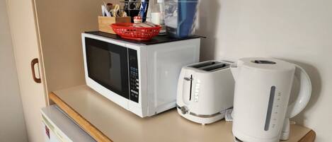 Een kitchenette met een magnetron, toaster en koffiezetapparaat op een aanrecht.
