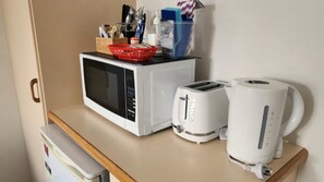 A kitchenette with a microwave, toaster, and coffee maker on a countertop. - Jopen Motel Unit 4 ~ Stress-free and comfortable accommodation! (Sussex Inlet)