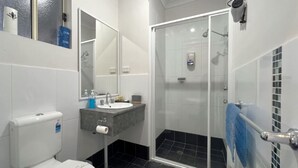 Une salle de bain équipée de toilettes, d’un lavabo, d’un miroir et d’une douche.