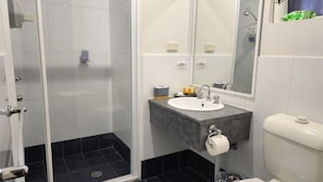 Ein modernes Badezimmer mit Duschkabine aus Glas, einem Waschbecken mit Marmorplatte und einer Toilette.