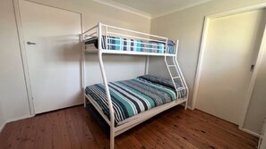 A bunk bed with a ladder, a door, and a wooden floor.