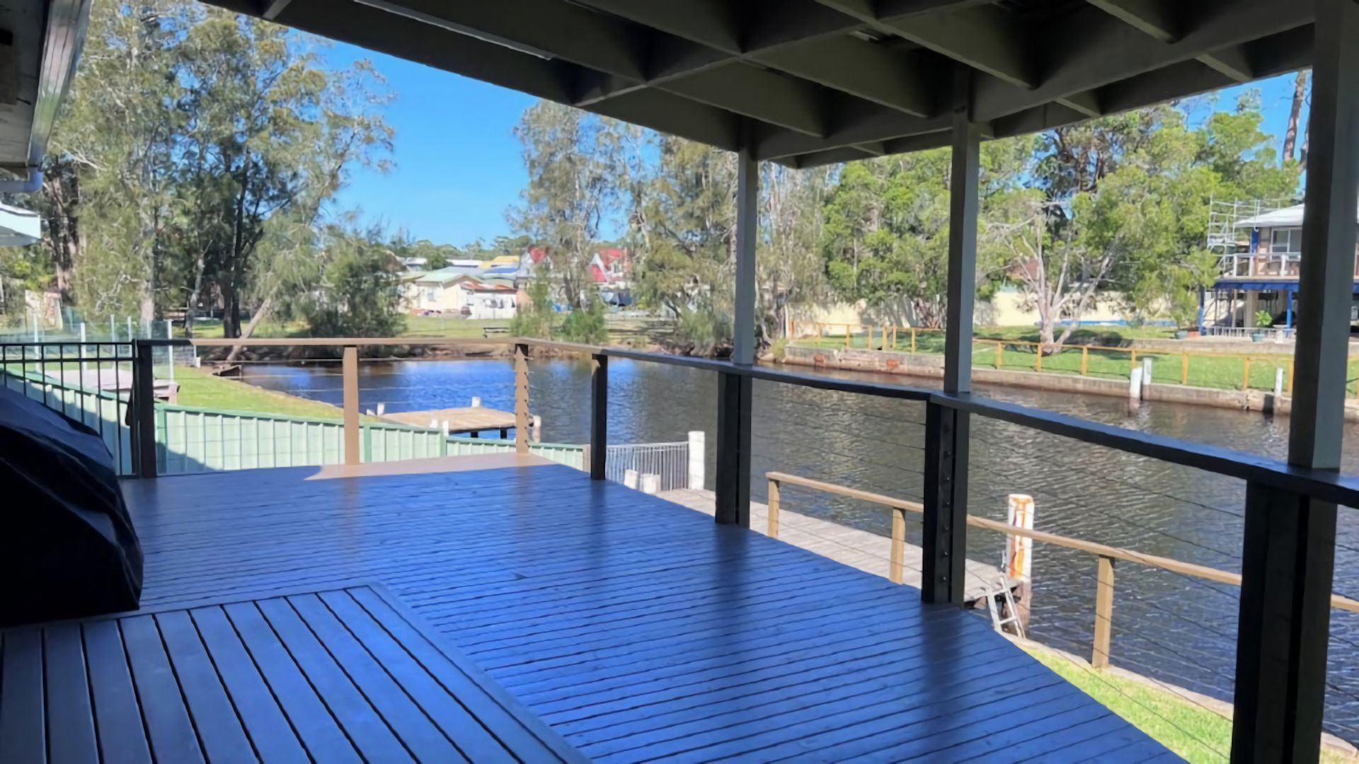 A covered deck with a view of a river and surrounding greenery.
