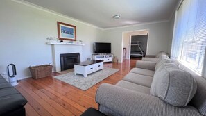 Ein Wohnzimmer mit Kamin, Fernseher, Sofa und Blick auf eine Treppe.