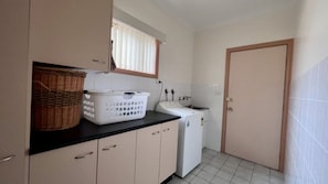 A laundry room with a washing machine, a drying machine, a basket, and a cabinet. - Sought After Location (Berrara)