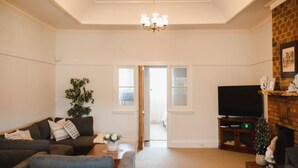 A living room with a sofa, a coffee table, a TV, a fireplace, and a door leading to another room.