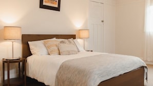 A neatly made bed with a wooden headboard, two bedside lamps, and a framed picture on the wall.