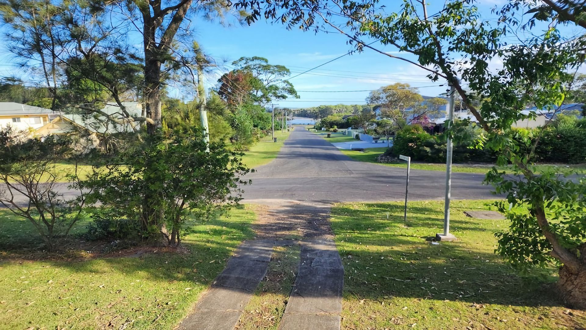 A residential street with houses on both sides, a sidewalk, and trees.