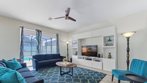 A modern living room with a sofa, chairs, a coffee table, and a TV. - Storey Lake Resort | 6BR Villa w/ Pool Near Disney (Kissimmee)