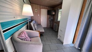 Ein Zimmer mit einer Couch, einem Bett, einem Fernseher und einem Ventilator.