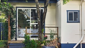 A residential building with a glass door, a small window, and a potted plant in the foreground.