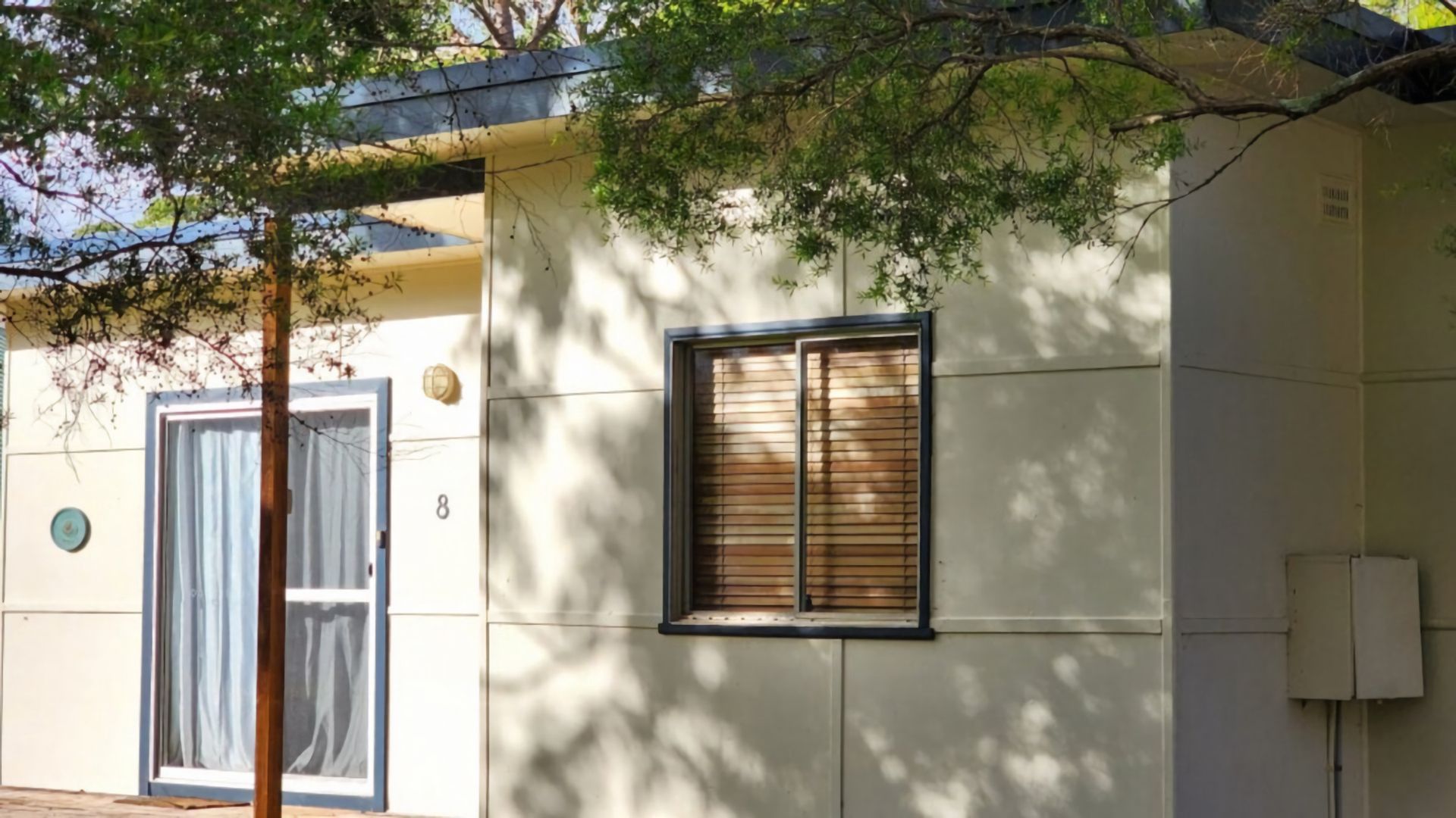 A building with a door, a window with blinds, and a number '8' on the wall.