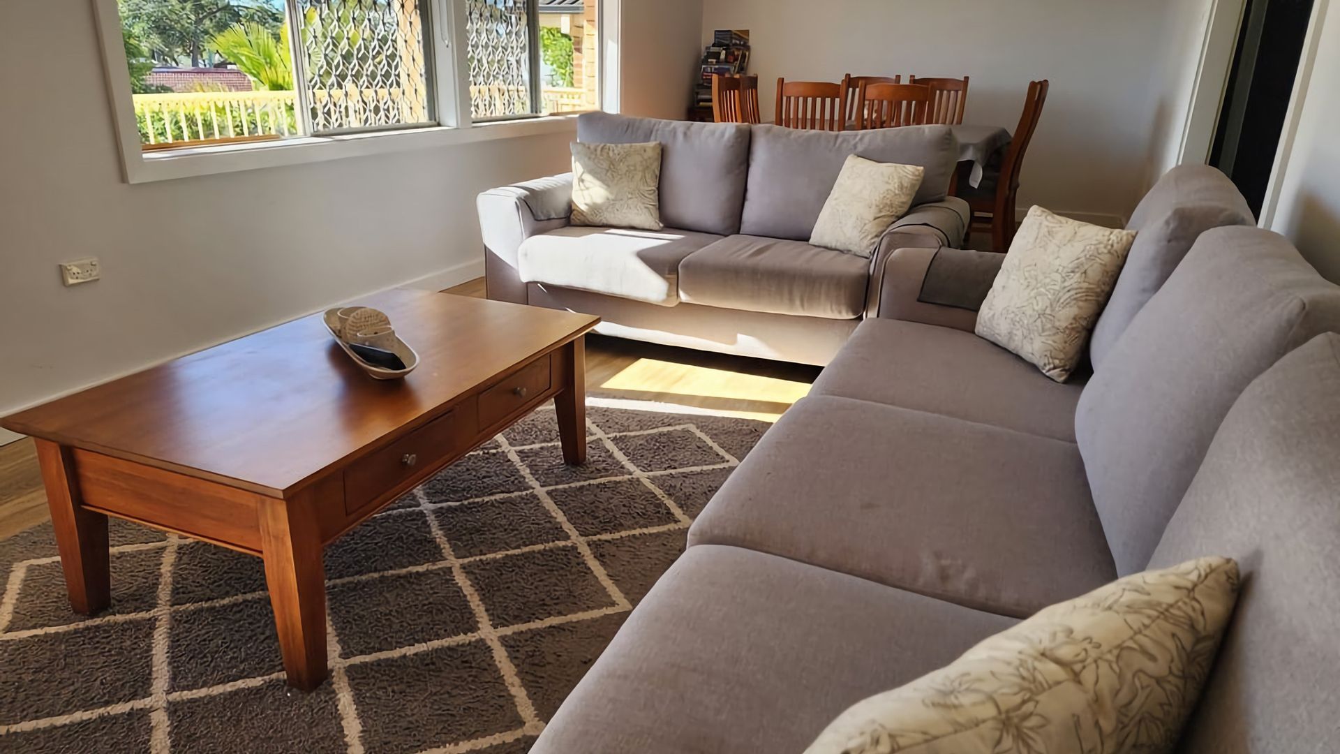 Una sala de estar con un sofá, una mesa de centro y un comedor con sillas.