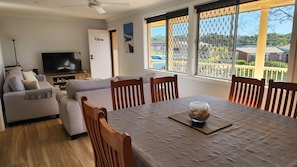 A living room with a sofa, TV, and dining area with chairs and a table.