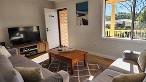 A living room with a flat-screen TV, a wooden coffee table, and a sofa.