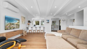 Una sala de estar moderna con un sofá color beige, un sillón negro y amarillo, y una mesa de centro de madera.