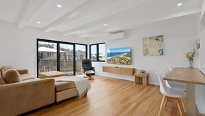 Amplia sala de estar con televisor grande, zona de comedor y balcón con vistas al mar.