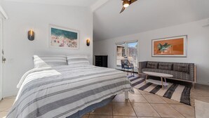 Un dormitorio con una cama, ventilador de techo, sofá y ventana.