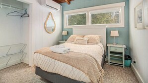 A bedroom with a bed, bedside tables, a hanging light, and a window.
