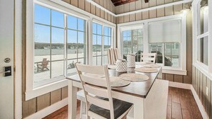 A dining area with a table set for four, large windows, and a view of the outdoors.