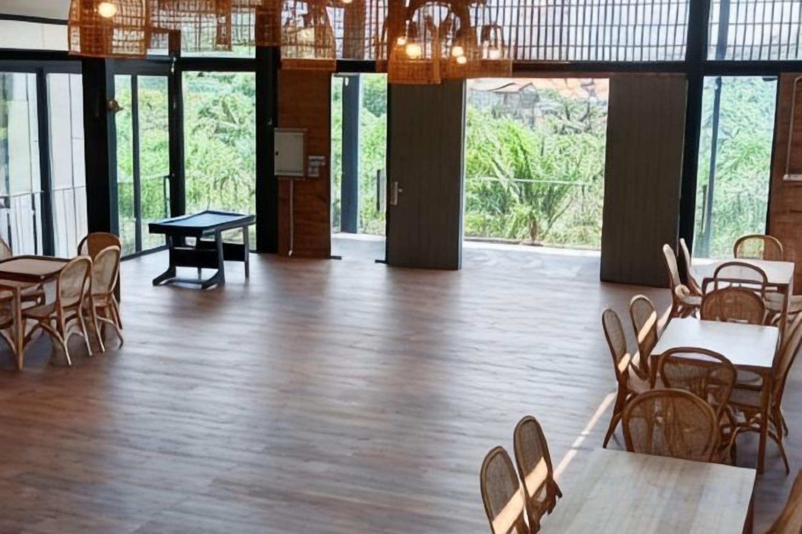A spacious indoor area with wooden flooring, tables, chairs, and a ping pong table.