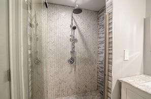 A shower with a herringbone tile pattern, a glass door, and a marble countertop in the adjacent bathroom. - Lovely 4-bedroom house in Meriden (Meriden)