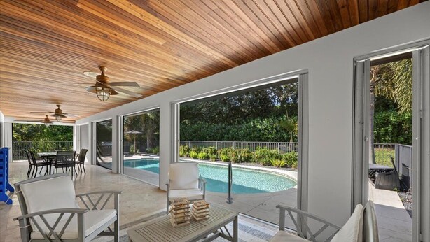 Un'area esterna coperta con piscina, posti a sedere e ventilatori a soffitto.