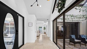 Un interno moderno con un corridoio che conduce a una zona relax, una porta in vetro e un cartello con la scritta 'STAY'.