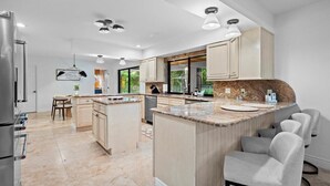 Una cucina moderna con isola centrale, elettrodomestici integrati e zona pranzo con vista sull'esterno.
