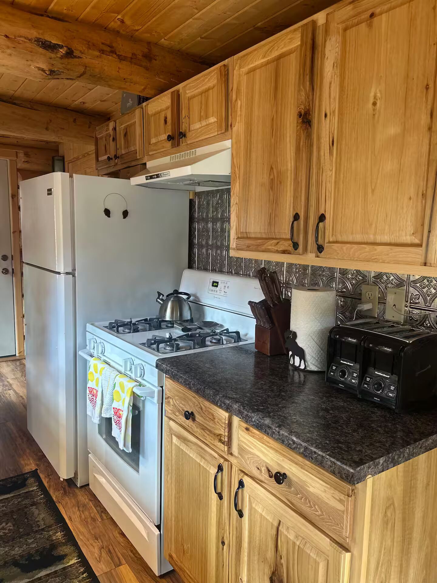 Una cocina con armarios de madera, un refrigerador blanco, una estufa y un tostador.