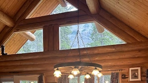 A wooden interior with a large dining table, chairs, and a hanging light fixture. - Lamar Valley Mountain Cabin (Silver Gate)