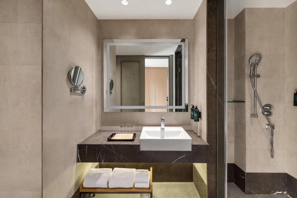 A modern bathroom with a large mirror, a sink, and a shower.