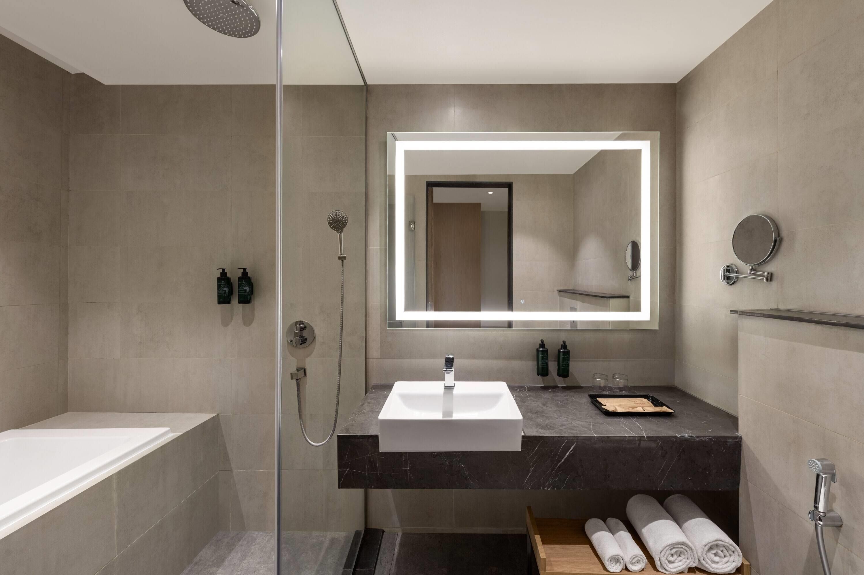 Un baño moderno con una bañera, un lavamanos con un espejo grande y una ducha.