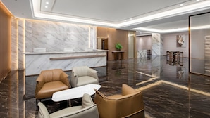 A modern lobby with marble walls, leather seating, and a reception desk. - Days Inn by Wyndham Zhuhai Qinglv Road (Zhuhai)