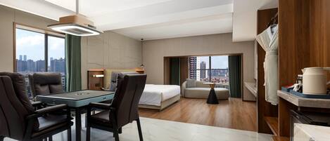 A modern hotel room with a dining area, a bed, a sofa, and a view of the city skyline.