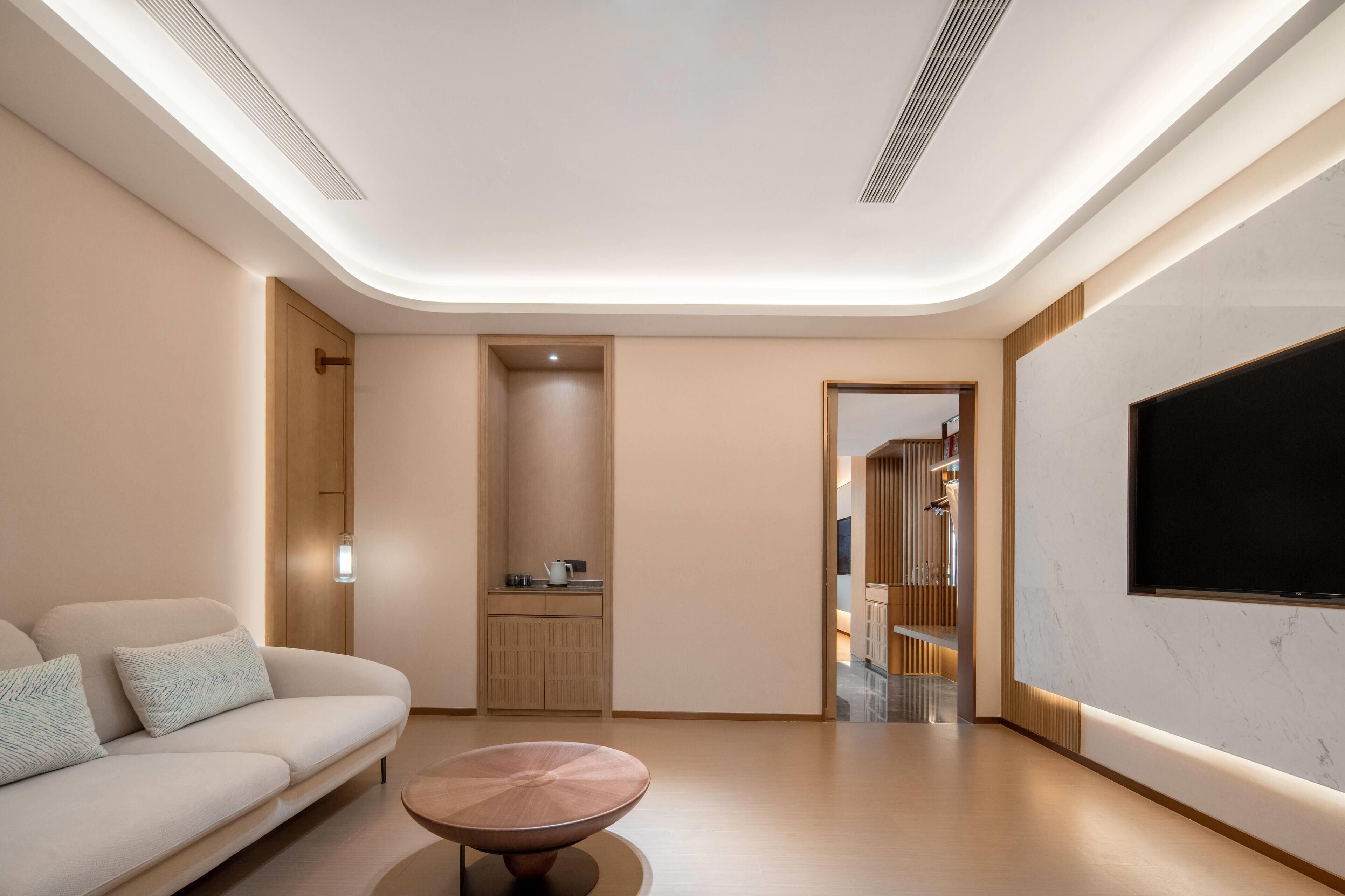 Una sala de estar moderna con un sofá, una mesa de centro, un televisor y una zona de cocina.