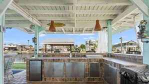 An outdoor kitchen area with a grill, a sink, and a trash can. - The Gulf Breeze - Direct Access To Gulf (Hernando Beach)