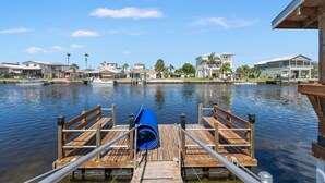 A wooden dock with a blue barrel, calm water, and houses in the background. - The Gulf Breeze - Direct Access To Gulf (Hernando Beach)