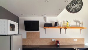 Una cocina moderna con microondas, horno y un reloj en la pared.
