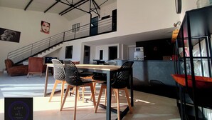 Amplia sala de estar con mesa y sillas de comedor, una escalera y una cocina.