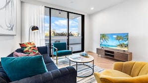 Een moderne woonkamer met een bank, fauteuils, een salontafel en een televisie.