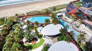 Ein Resort mit großem Pool, Palmen und Blick auf den Strand.