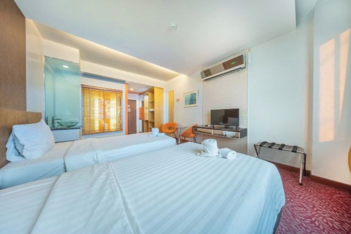 A hotel room with two beds, a TV, a desk, and a chair.