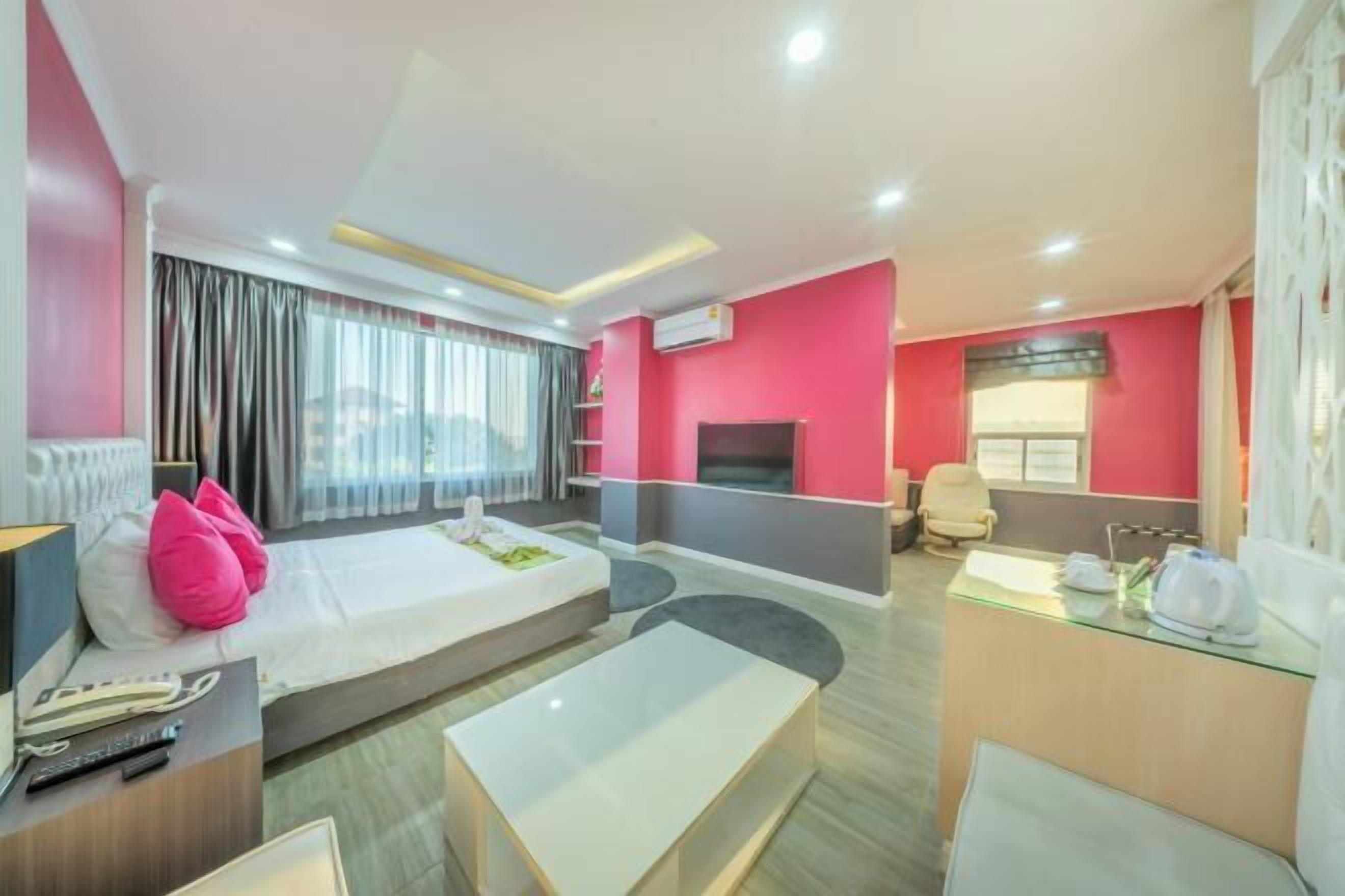 A hotel room with a bed, a desk, a chair, a TV, and a window with curtains.